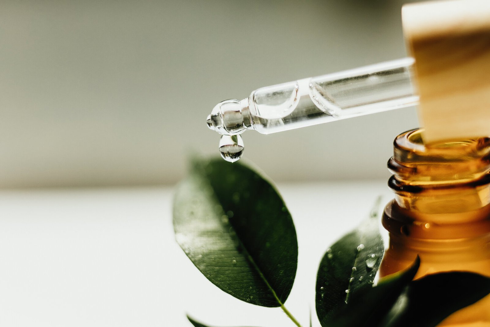 Amber bottle with serum or essential oil and green leaf